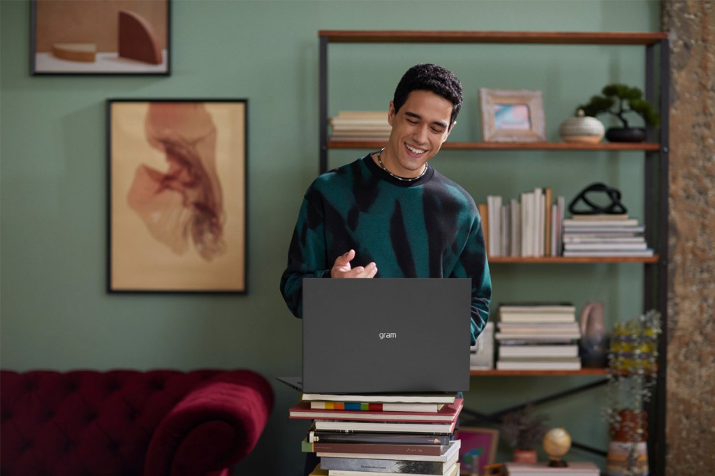 Ein junger Mann arbeitet in seinem Wohnzimmer an einem LG Gram Notebook.