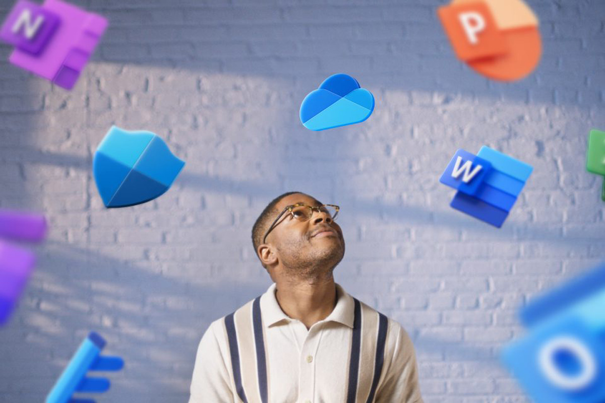 Ein Mann steht vor einer Wand, um ihn herum fallen Logos der Microsoft-Produkte von der Decke.