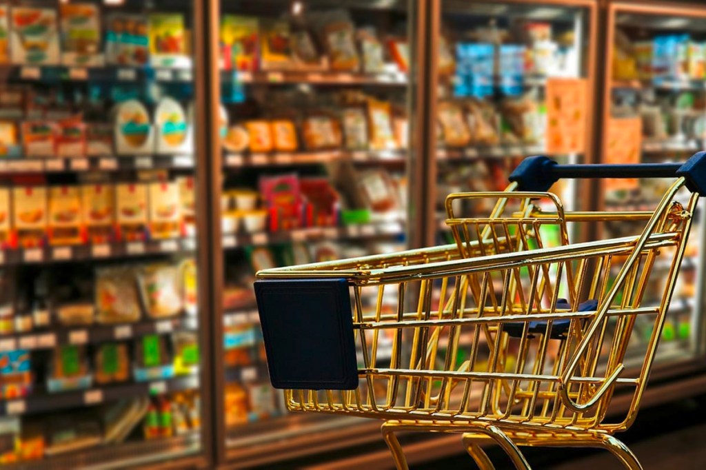 Supermarktszene mit Einkaufswagen vor Kühlregal mit Mogelpackungen