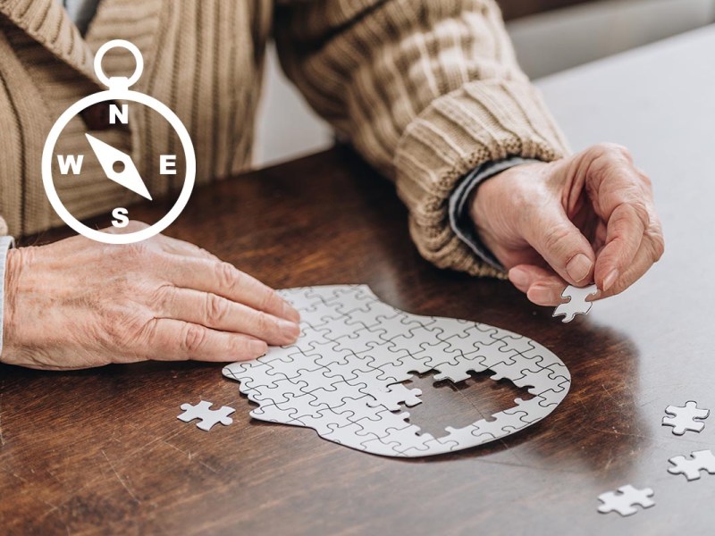 Ein älterer Herr legt ein Puzzle in Form eines Gehirns.