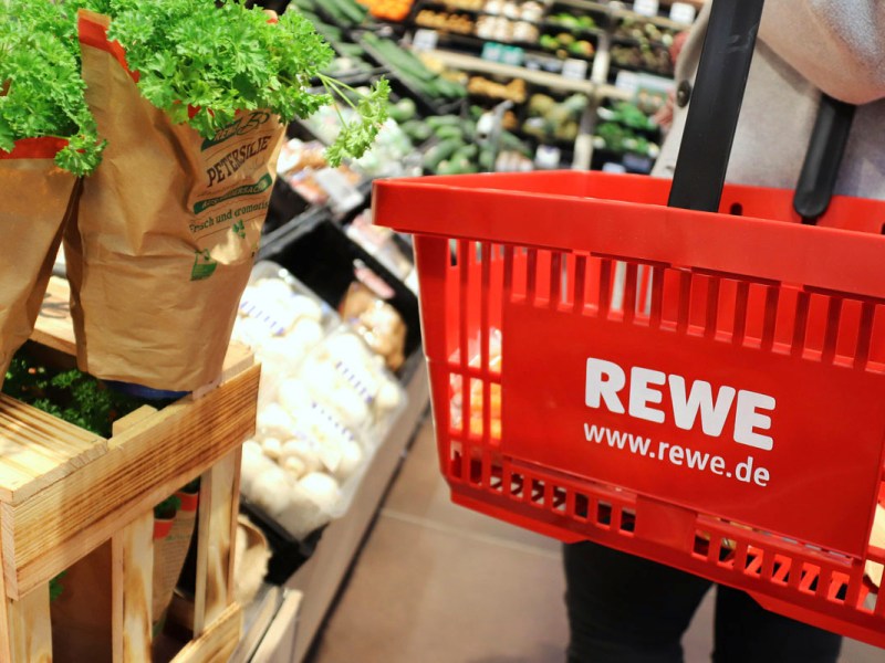 Eine Frau kauft bei Rewe Lebensmittel ein.