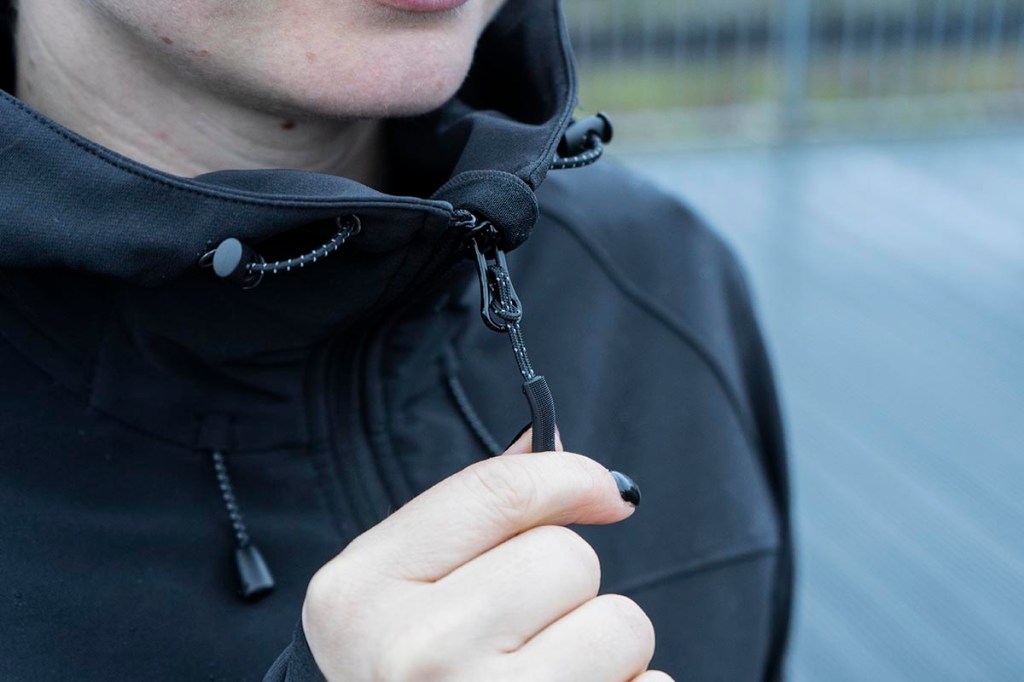 Detailbild Frau hat den Reißverschluss bei einer Softshell-Jacke komplett hochgezogen.