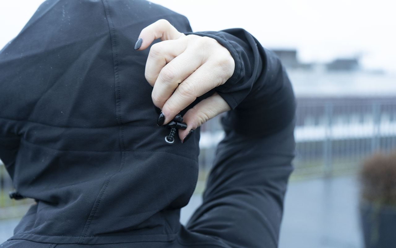 Die Detailansicht einer Softshell-Jacke zeigt das enger Stellen der Kapuze der Jacke.