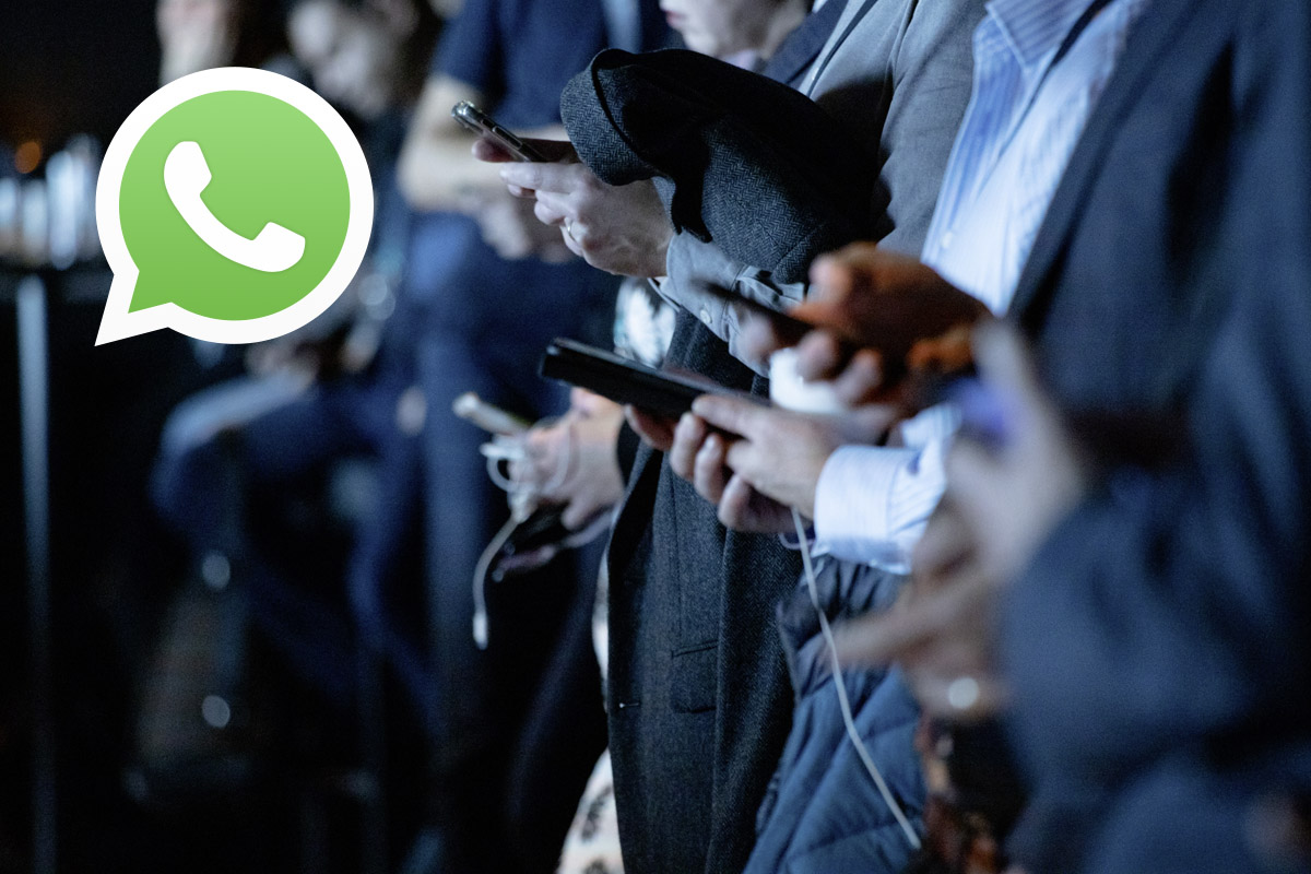 Mehrere Personen stehen in einer Reihe und tippen auf einem Smartphone.