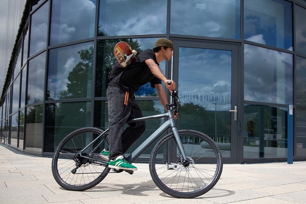 Mann fährt auf dem E-Bike Sydney von coboc an einer gläsernen HÄuserfront vorbei