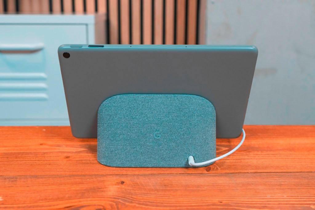 Grau blaues Google Tablet von hinten angelehnt an gleichfarbiger Docking-Station auf Holztisch