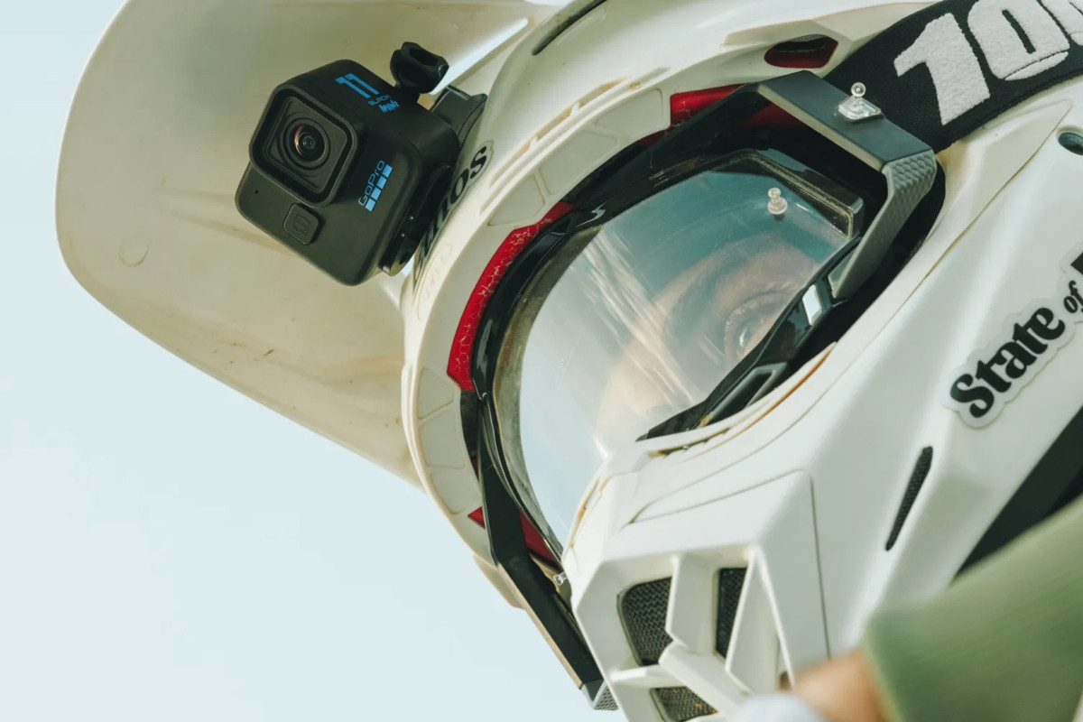 Mann mit weißem Motorradhelm von schräg unten mit schwarzer GoPro-Mini Kamera vorne dran