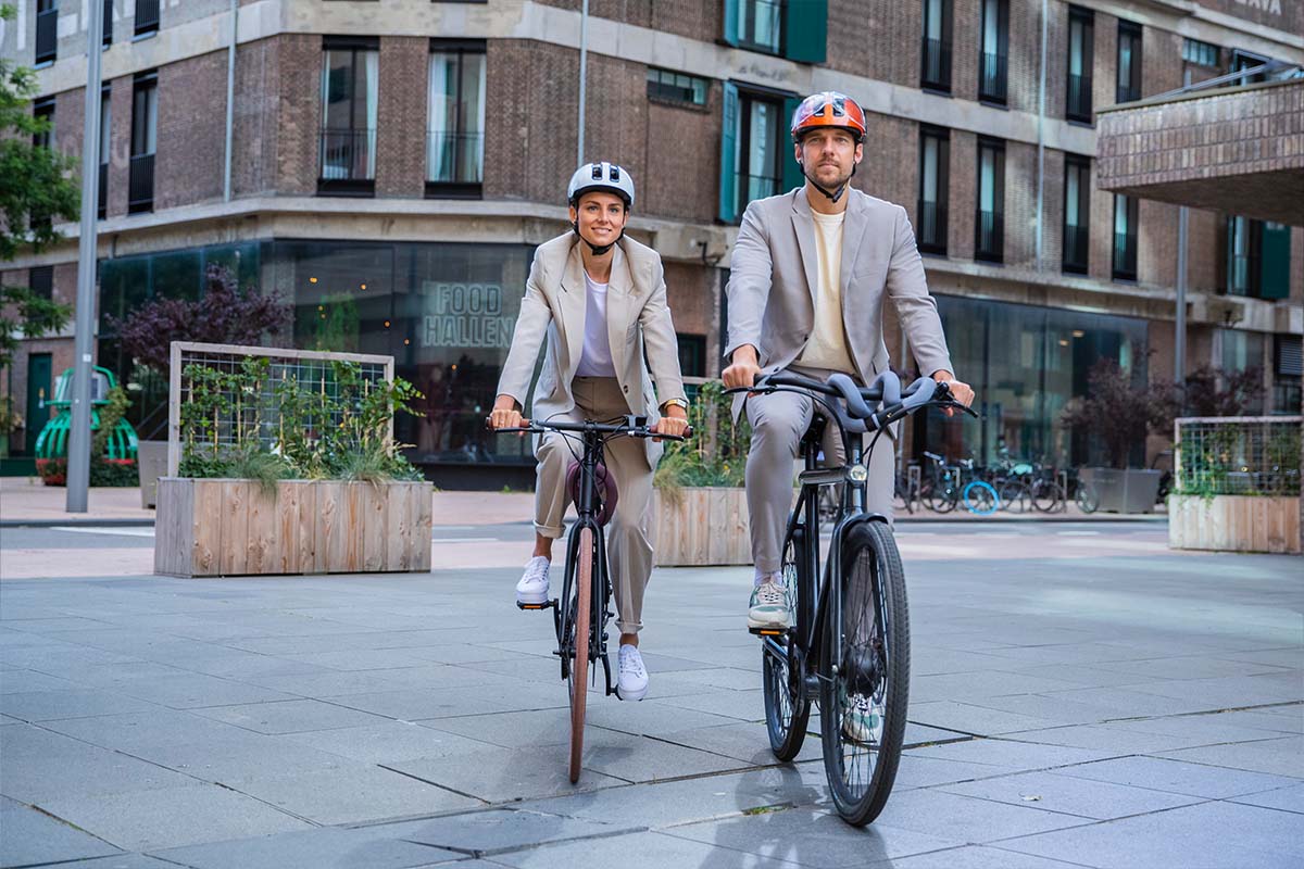 Zwei Radfahrer in der Stadt, beide tragen Helm von Abus Hud-Y ace
