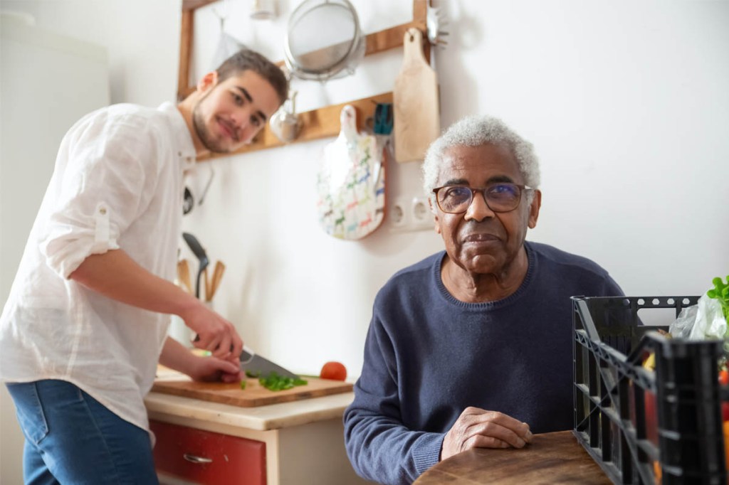 Ein junger und ein alter Mann kochen zusammen in der Küche.