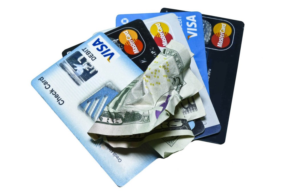 Aufgefächert liegen einige Kreditkarten sowie ein zerknüllter Geldschein.