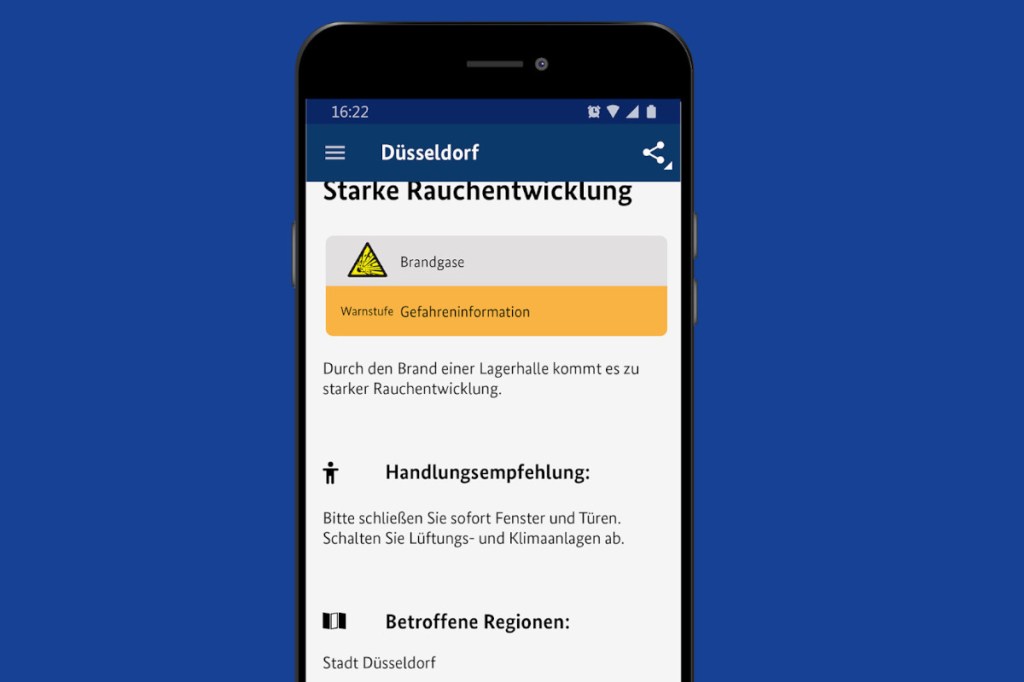 Dunkles Smartphone zeigt App mit Verhaltenstipps bei Rauchentwicklung auf blauem Hintergrund