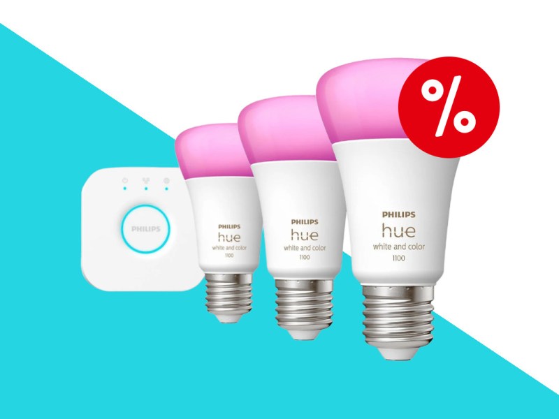 Drei Philips Hue Lampen mit weißem Sockel und pink leuchtenden LEDs in Reihe versetzt aufgestellt mit weißem quadratischem Gerät am linken Ende der Reihe auf türkis weißem Hintergrund mit rotem Prozentzeichen rechts oben