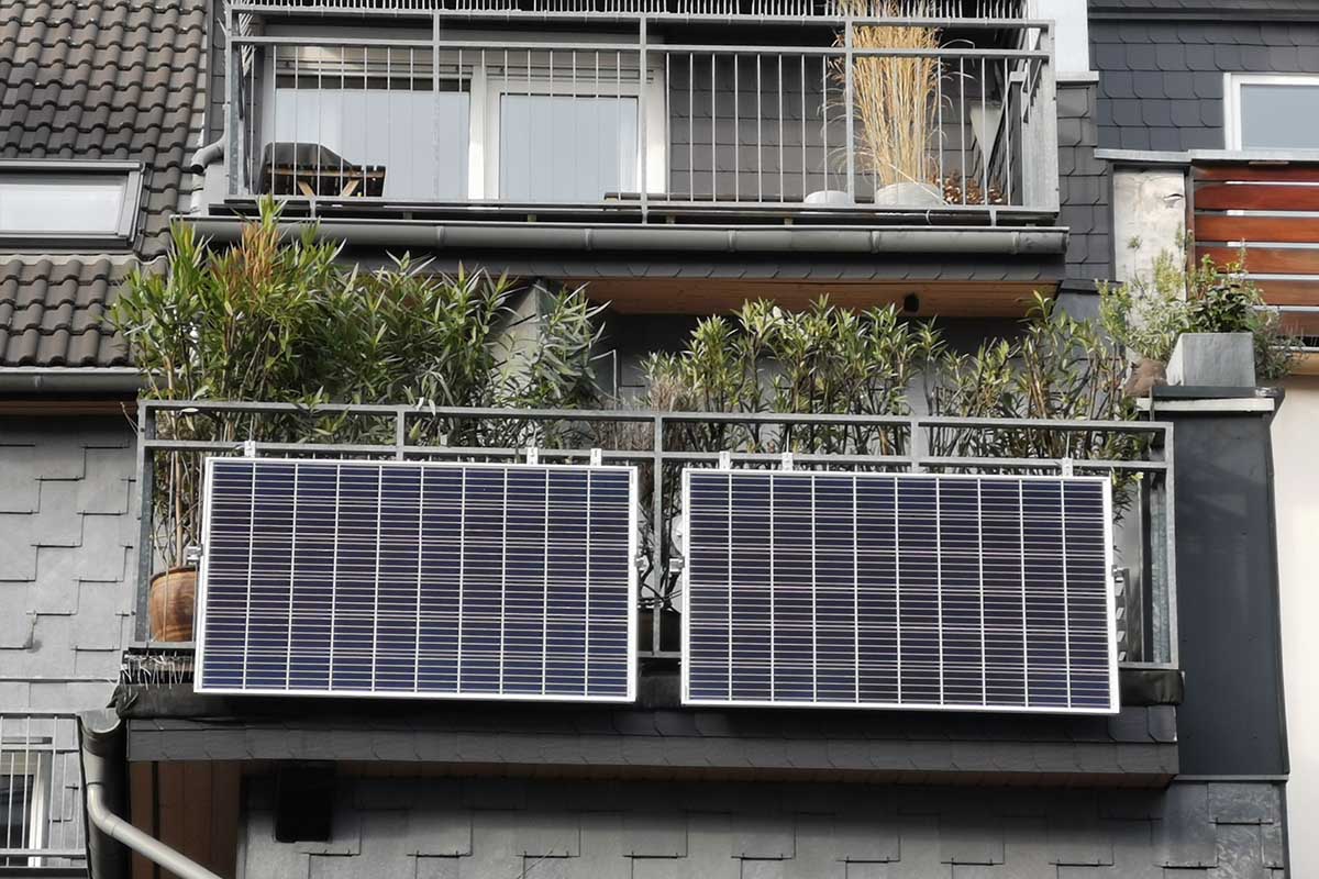 Ein Haus von vorne mit Balkon und zwei installierten Solarpanels.