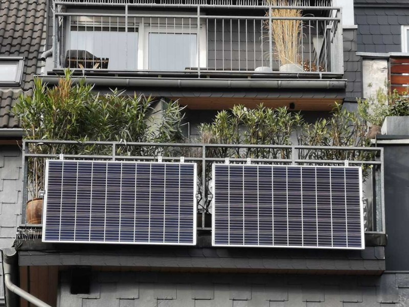 Ein Haus von vorne mit Balkon und zwei installierten Solarpanels.
