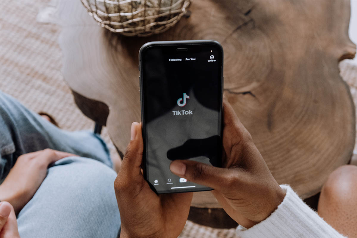 Zwei Hände halten ein Smartphone auf dem TikTok geöffnet ist.