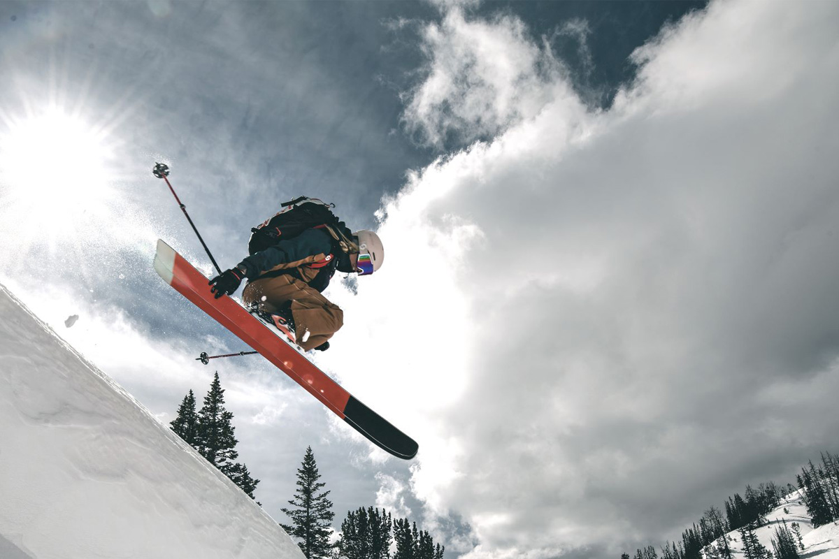 Eine Frau springt mit Skiern über einen Berg.
