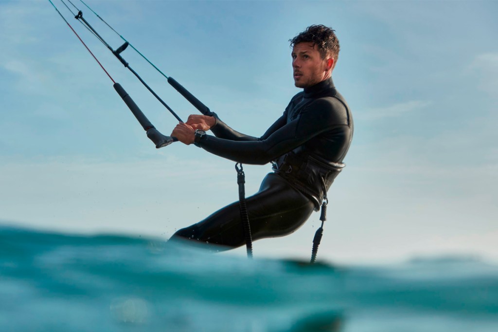 Ein Mann steht auf einem Kitesurfboard im Wasser.