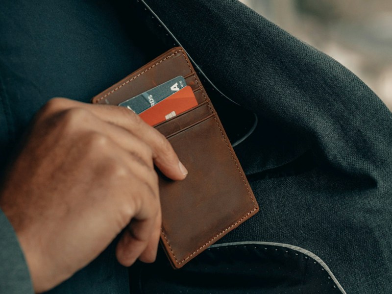 Ein Mann zieht eine Brieftasche mit Geldkarten aus dem Jackett.