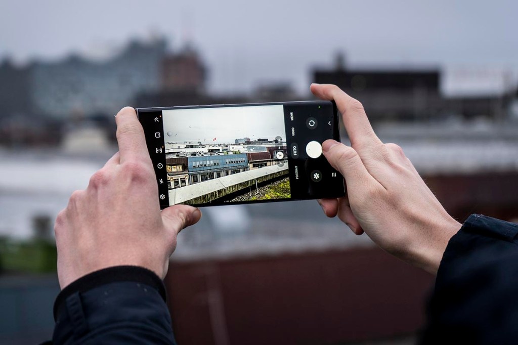 Galaxy S23 Smartphone wird von einem Mann zum Fotografieren auf Dachterrasse genutzt.