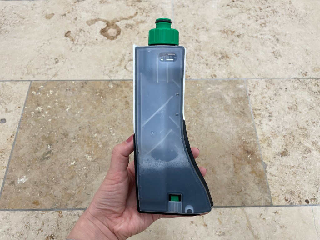 Hand hält Flasche mit dreckigem Wasser