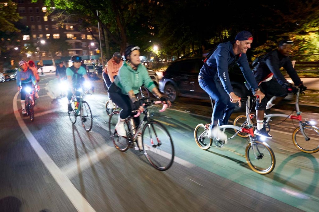 mehrere Menschen fahren mit dem Rad durch das nächtliche New York