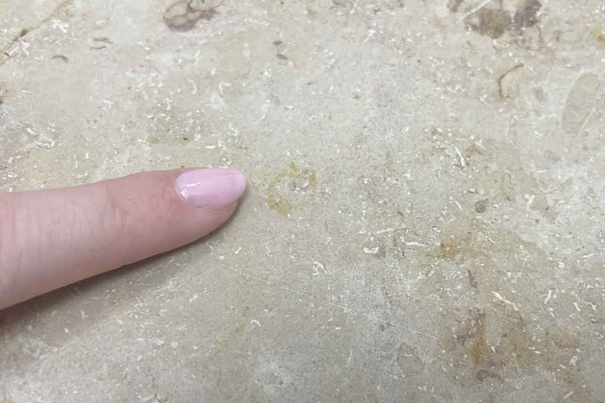 Ein Finger zeigt auf Schmutzrückstände am Boden.