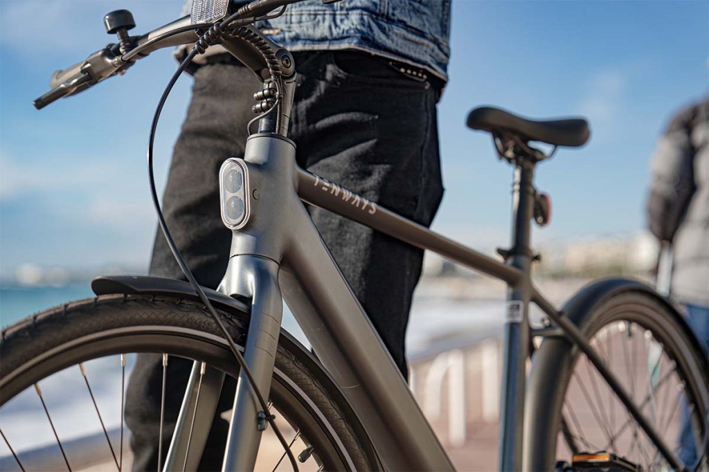 E-Bike CGO600 Pro von vorne im Anschnitt, dahinter steht eine person in der Stadt