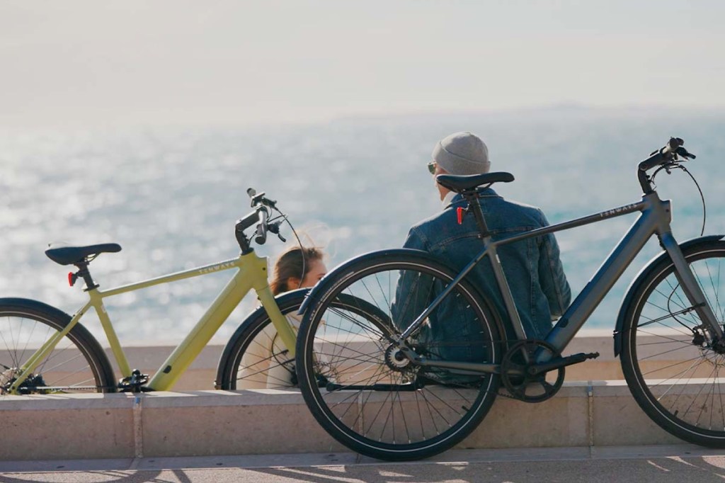 Zwei Menschen sitzen an einer Hafenkante, im Vordergrund stehen ihre E-Bikes von Tenways, Modell CGO600 Pro