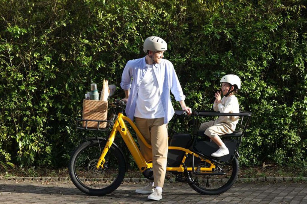 Vater mit E-bike PakPak E+ von Momentum stehend, guckt sich zu seinem Kind auf dem Rücksitz um