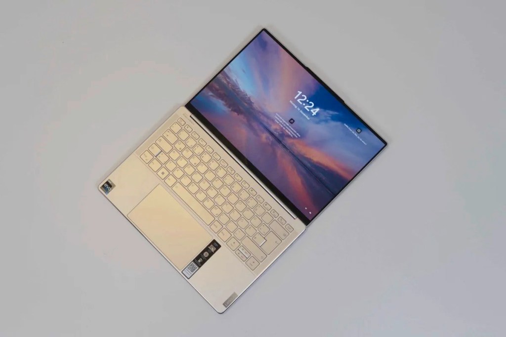 Aufgeklapptes helles Notebook mit lila Bildschirm von oben auf grauem Tisch