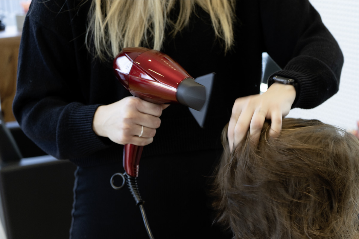 Die Friseurmeisterin testet einen Haartrockner.