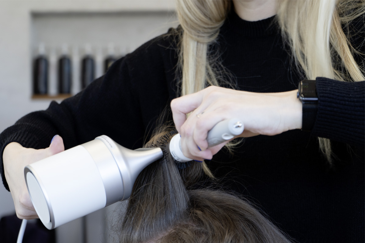 Die Friserumeisterin testet einen Haartrockner.