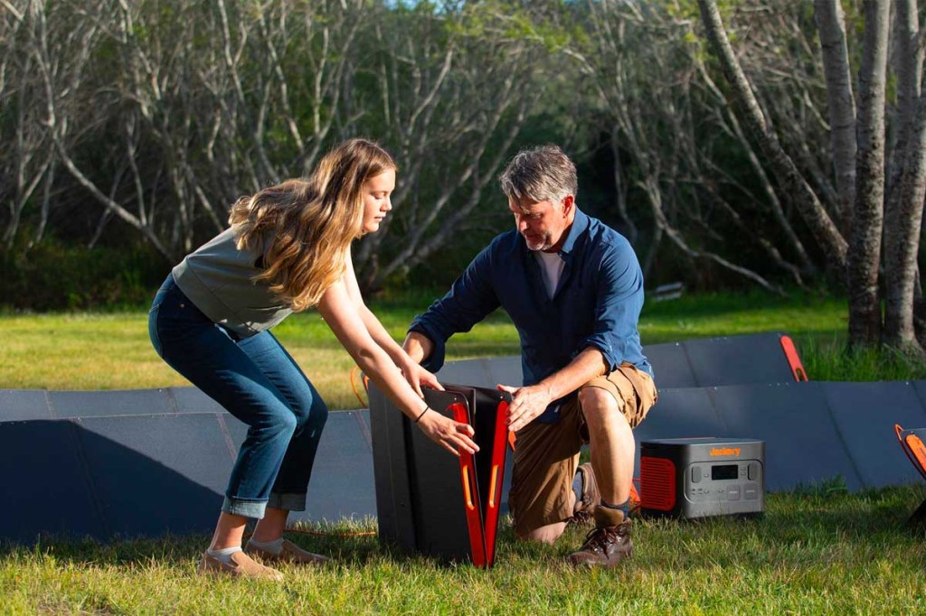 Zwei Personen bauen mehrere mobile Solarpanels auf.