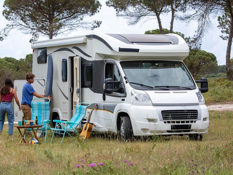 Camper auf einer Wiese mit zwei Menschen