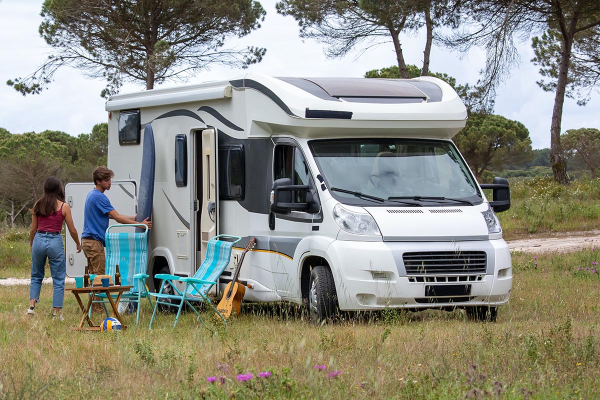 Camper auf einer Wiese mit zwei Menschen