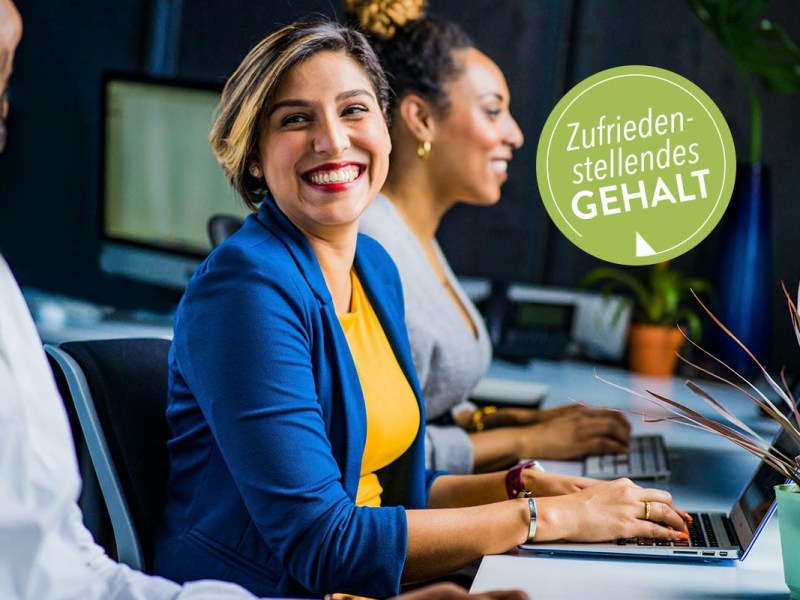 Zwei lächelnde Frauen am Arbeitsplatz vor einem Laptop