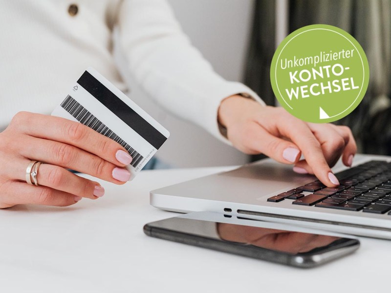 Frau an einem Laptop mit Bankkarte in der Hand