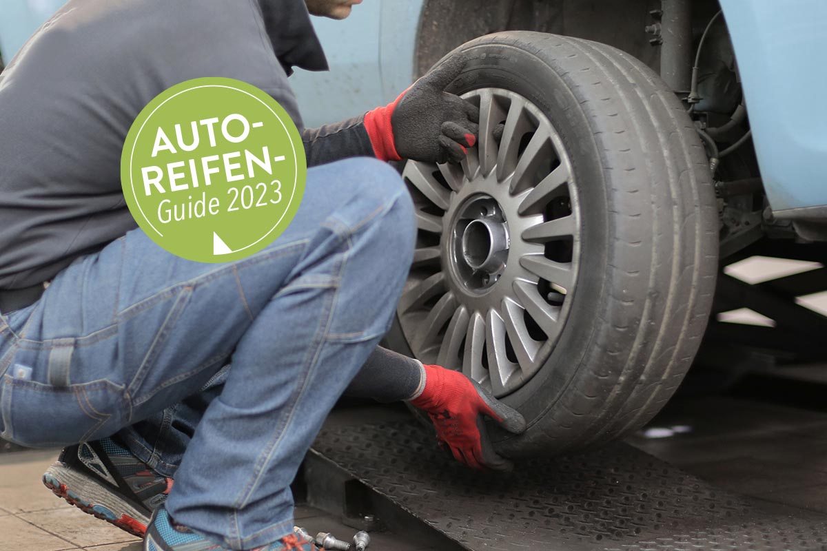 Person wechselt einen Reifen an einem Auto