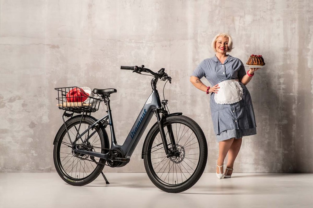Frau mit einem Kuchen in der hand steht neben einem FAhrrad