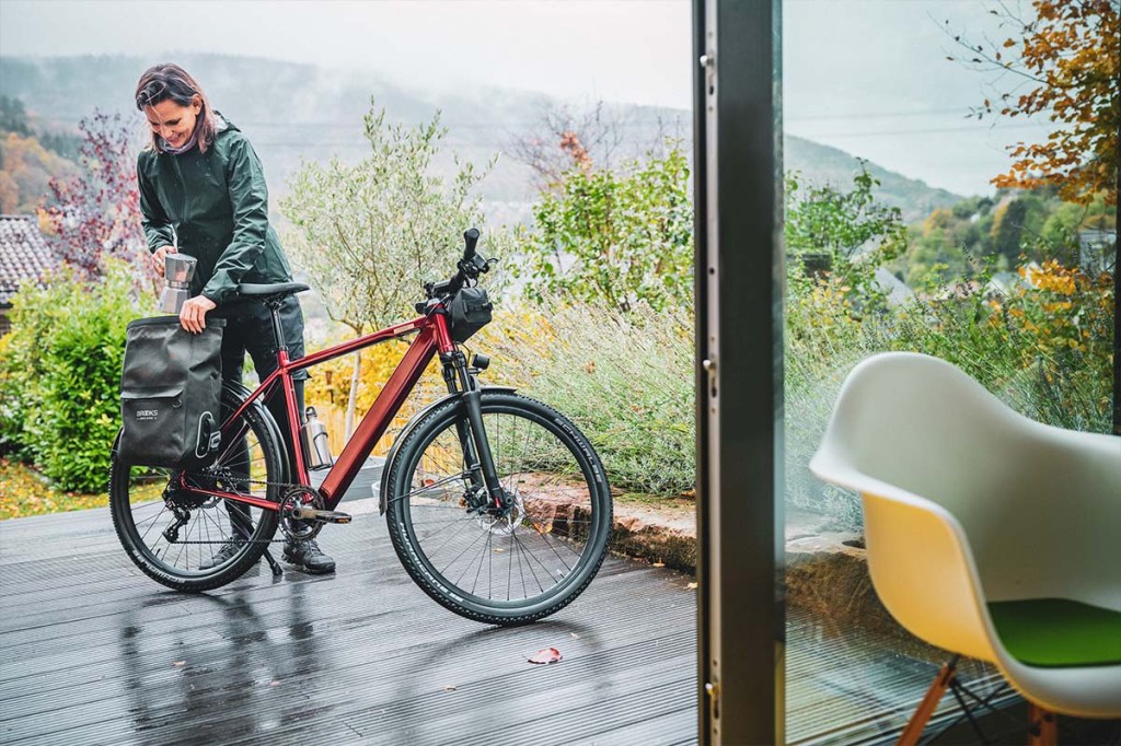Frau steht auf ihrer Terasse und bepackt ihr E-bike