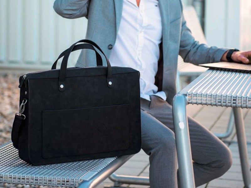 Ein Mann sitzt auf einer Bank, daneben die Laptop-Tasche Classy von Hama.