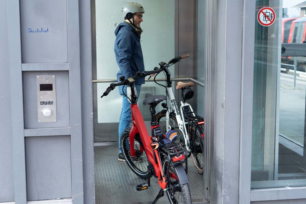 Mann mit zwei kompakten E-Bikes im Fahrstuhl