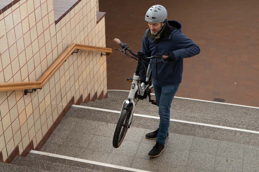 Mann trägt kompaktes E-Bike die Treppe hoch