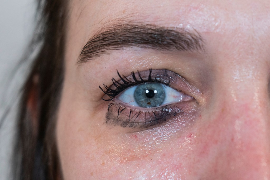 Blaues Auge von Frau mit verschmiertem Mascara.