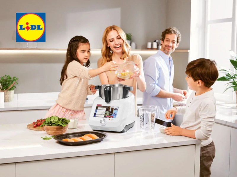 Eine vierköpfige Familie, ein Vater und eine Frau mit zwei Kindern die in der Küche mit dem Monsieur Cuisine hantieren.