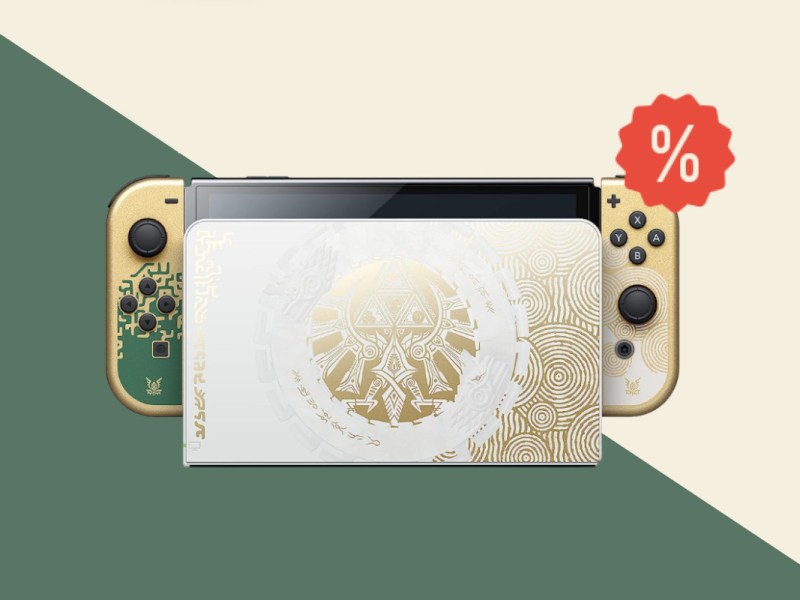 Beige Weiße Nintendo Switch in Ladestation auf grün beigem Hintergrund mit rotem Prozentzeichen rechts oben