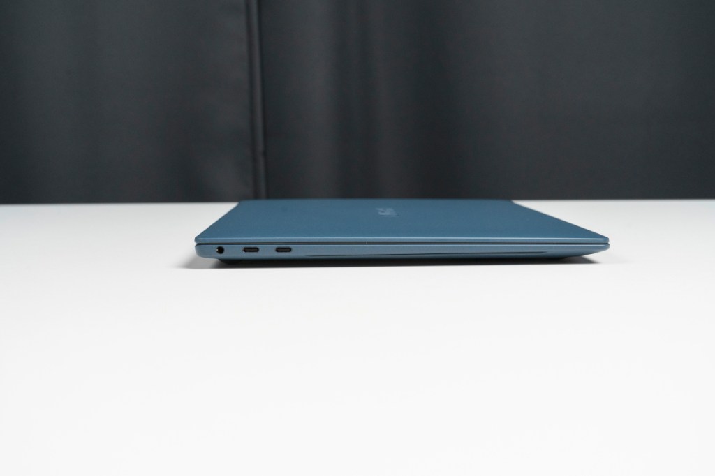 blaues zugeklapptes Notebook auf weißem Tisch von der Seite