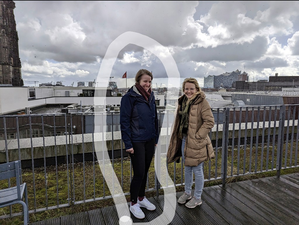 Zwei Frauen auf Terrasse bei Regen schauen in die Kamera