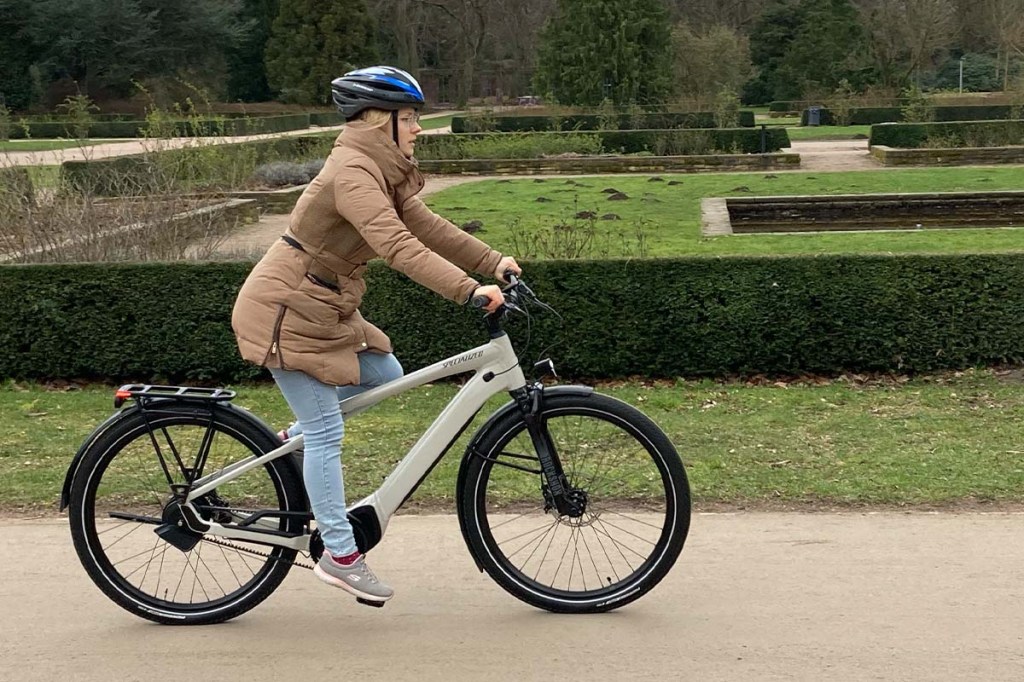 Frau fährt mit einem E-Bike durch einen Park
