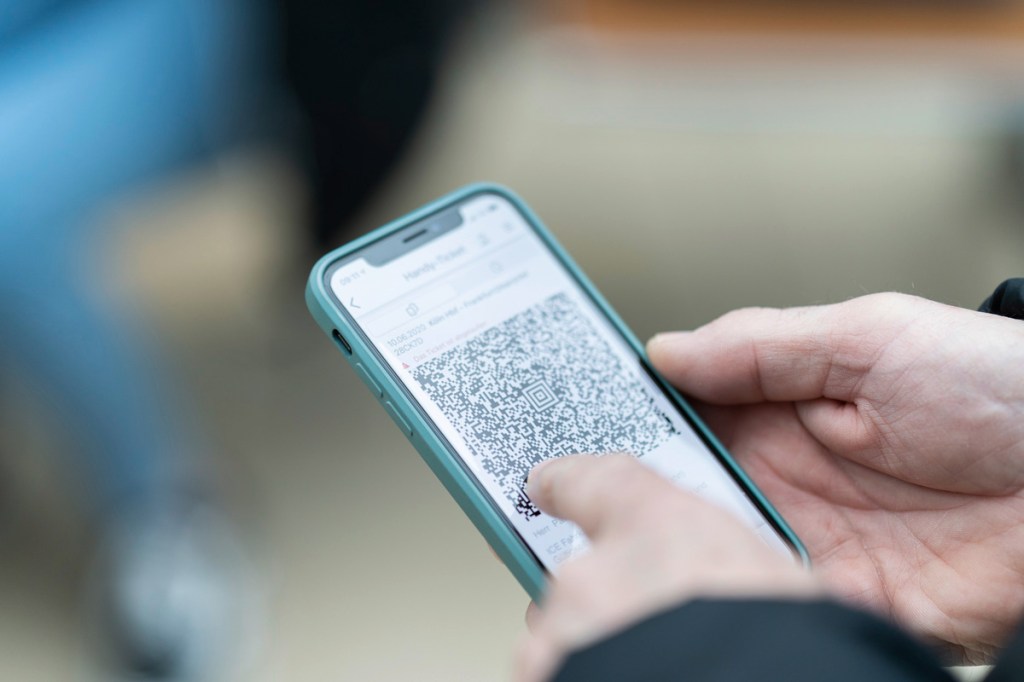 Eine Person tippt auf einen QR Code auf dem Handy.